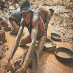 A gold miner scoops mud while digging an open pit at the Chudja mine in the Kilomoto concession near the village of Kobu, 100 km (62 miles) from Bunia in north-eastern Congo,