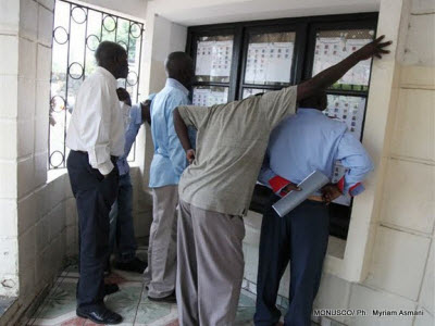 People look for their names on a voters' list at a polling center in Goma